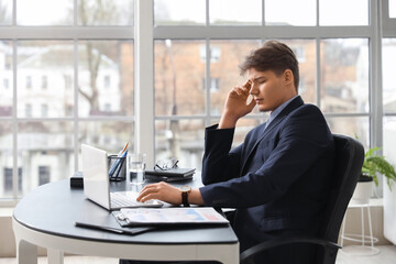 Tired young businessman suffering from headache in office