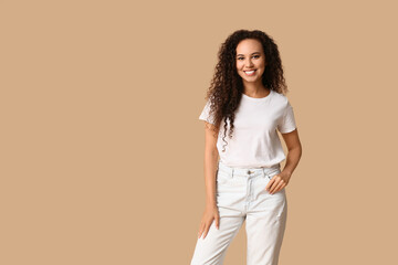 Happy young African-American woman on beige background
