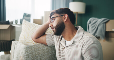Boxes, depression and thinking with man on sofa in living room of home for mortgage failure or...