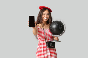 Obraz premium Young Asian woman with globe and mobile phone on white background. Travel concept