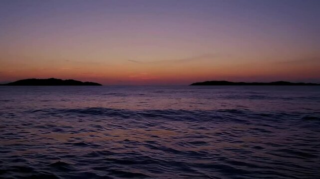Calm ocean waves at dusk with warm purple and orange tones in the sky.