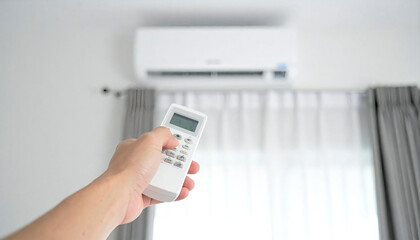 Fototapeta premium エアコンのリモコンを持つ手。快適な部屋の背景イメージ。Hand holding air conditioner remote control. Comfortable room background image.