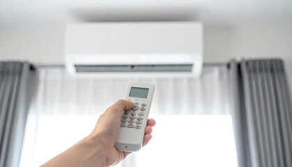 エアコンのリモコンを持つ手。快適な部屋の背景イメージ。Hand holding air conditioner remote control. Comfortable room background image.