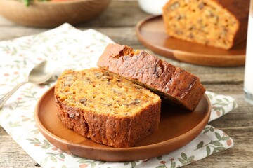 Pieces of homemade carrot cake with nuts and spoon on wooden table, closeup