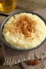 Delicious rice pudding with cinnamon, honey and almonds on wooden table, closeup