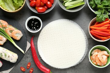 Rice paper sheets and different ingredients on dark grey table, flat lay