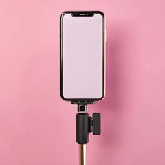 mobile phone with blank screen and selfie stick on pink background. mobile phone mockup.