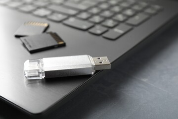 Usb flash drive, SD memory cards and laptop on grey textured table, closeup