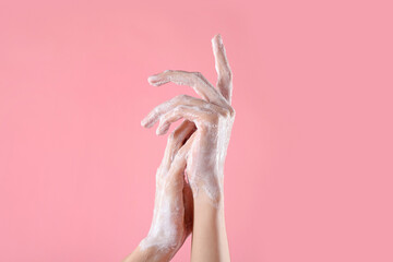Woman washing hands with soap on light pink background, closeup