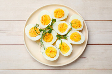Boiled eggs and microgreens on wooden table, top view