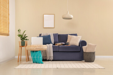 Cozy sofa and coffee table with laptop in interior of living room