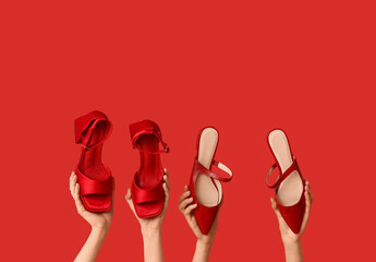 Female hands with stylish shoes on red background
