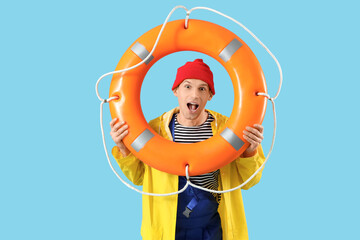 Shocked male sailor with rescue ring on blue background