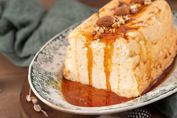 A detailed shot focuses on a traditional caramelized egg white pudding known as molotof or molotov, generously drizzled with rich syrup and decorated with whole and chopped almonds