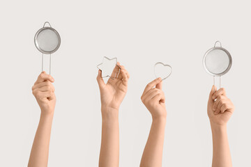 Female hands holding sieves with cookie cutters on white background