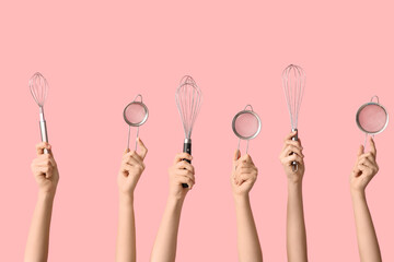 Female hands with sieves and whisks on pink background