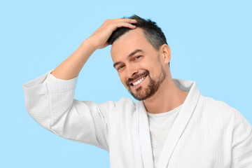 Smiling young man with hair loss problem on blue background