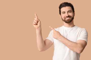 Young man pointing up on beige background
