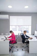 Caucasian young woman and man working each at their own desk. 
