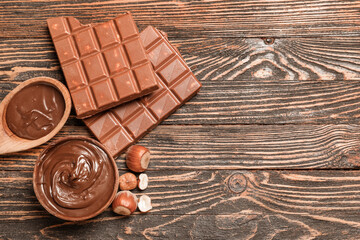 Bowl and spoon of sweet chocolate spread with hazelnuts on wooden background