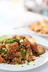 A plate of crispy pork belly stir fried with holy basil (kra pao moo grob), white rice and a fried egg at a street food stall at Soi 20 - Silom, Bangkok, Thailand