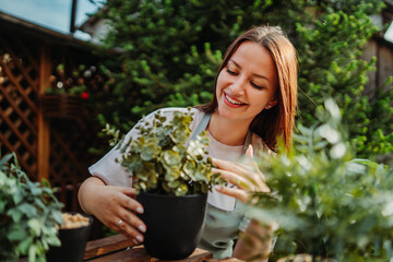 Young woman taking care of plants with water can and mister	
