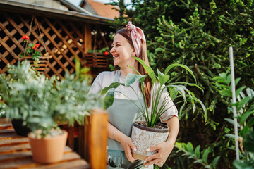 Young woman taking care of plants with water can and mister	
