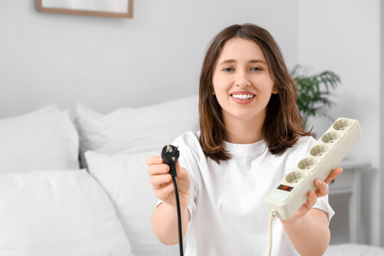 Young woman with plug and extension cord in bedroom. National Day of Unplugging