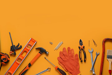 Gloves and construction tools on orange background