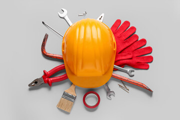 Hardhat and different construction tools on grey background