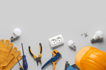 Hardhat, light bulbs and construction tools on grey background