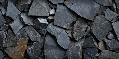 Close-up of dark gray, irregularly shaped stones, possibly slate, filling the frame.  Texture is rough and varied