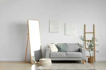 Beautiful interior of living room with sofa, stepladder and floor mirror