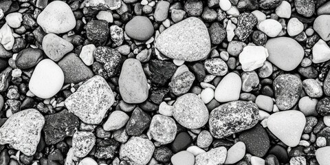Monochrome close-up of diverse smooth stones, varying in size and shade of gray, creating a textural background