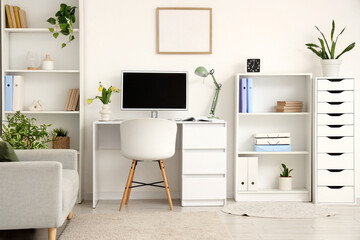 Interior of office with workplace, shelf units and sofa