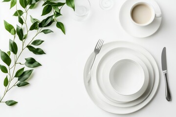 elegant table setting featuring minimalist white dinnerware flatware and vibrant green foliage