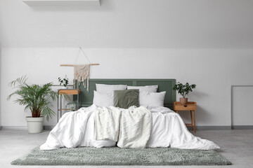 Interior of bedroom with bed, table and green plants