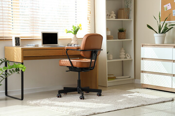 Interior of office with workplace, spring flowers in vase and shelf unit