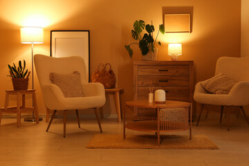 Interior of night living room with armchairs, commode, coffee table and glowing lamps near yellow...
