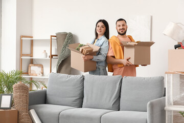 Happy young couple with boxes in room on moving day