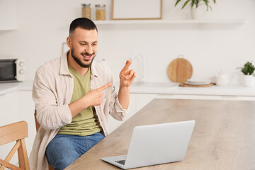 Young mute man using sign language during video call at home