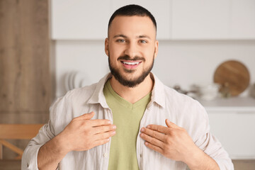 Young mute man using sign language at home