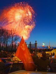 Saint-Petersburg, Russia - May 9 2025, Panoramic view of crowd of people watching fireworks in sky, Soviet flag flying in foreground, Summer Garden and Peter and Paul fortress, St Petersburg, Russia