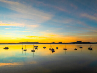 Sunrise with high cloud, boats and reflections over the water
