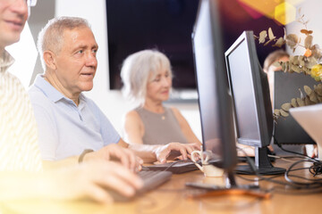 Computer lessons for elderly people in a nursing home. Group of seniors learning to use computers in class