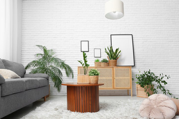 Interior of stylish living room with grey sofa, wooden cabinet, coffee table and houseplants in wicker baskets