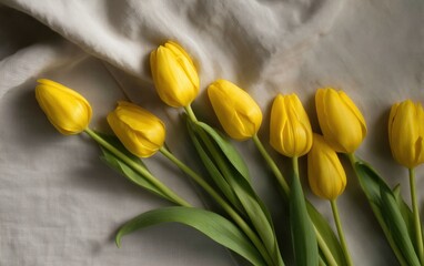 Obraz premium Bright Yellow Tulips on Linen Fabric with Soft Shadows, Minimalist Floral Arrangement from Top-Down Perspective