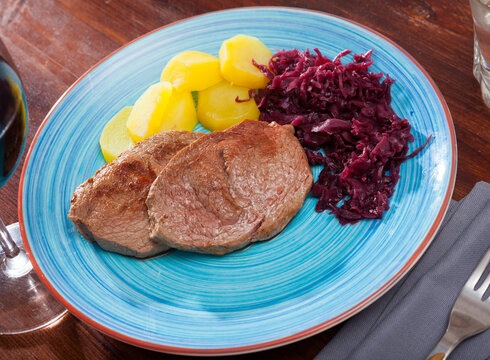 Veal Medallion de cadera with potato and sauerkraut..Healthy roasted beef steak served with baked potatoes and pickled cabbage..Grilled veal steak with boiled potato and marinated cabbage