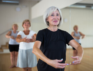 Obraz premium Portrait of a mature woman and people standing in the 1st position of the ballet stand at the mirror in a dance studio at a ..group lesson