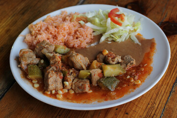 A flavorful pork dish served with rice and vegetables showcasing hearty ingredients that reflect the cultural richness and love for culinary delights in home-cooked meals.